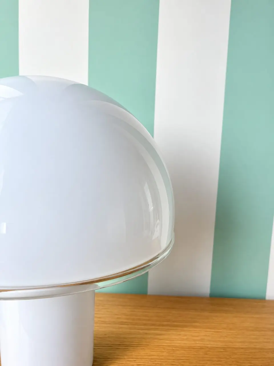Lampe champignon devant un mur rayé vert